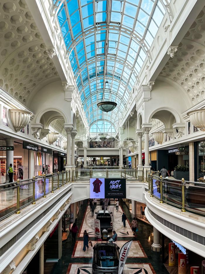 Elegant two-level shopping mall with glass dome ceiling and luxury stores.